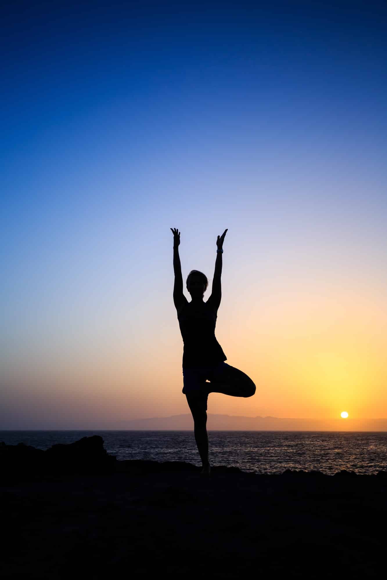 Woman exercising yoga sunset silhouette